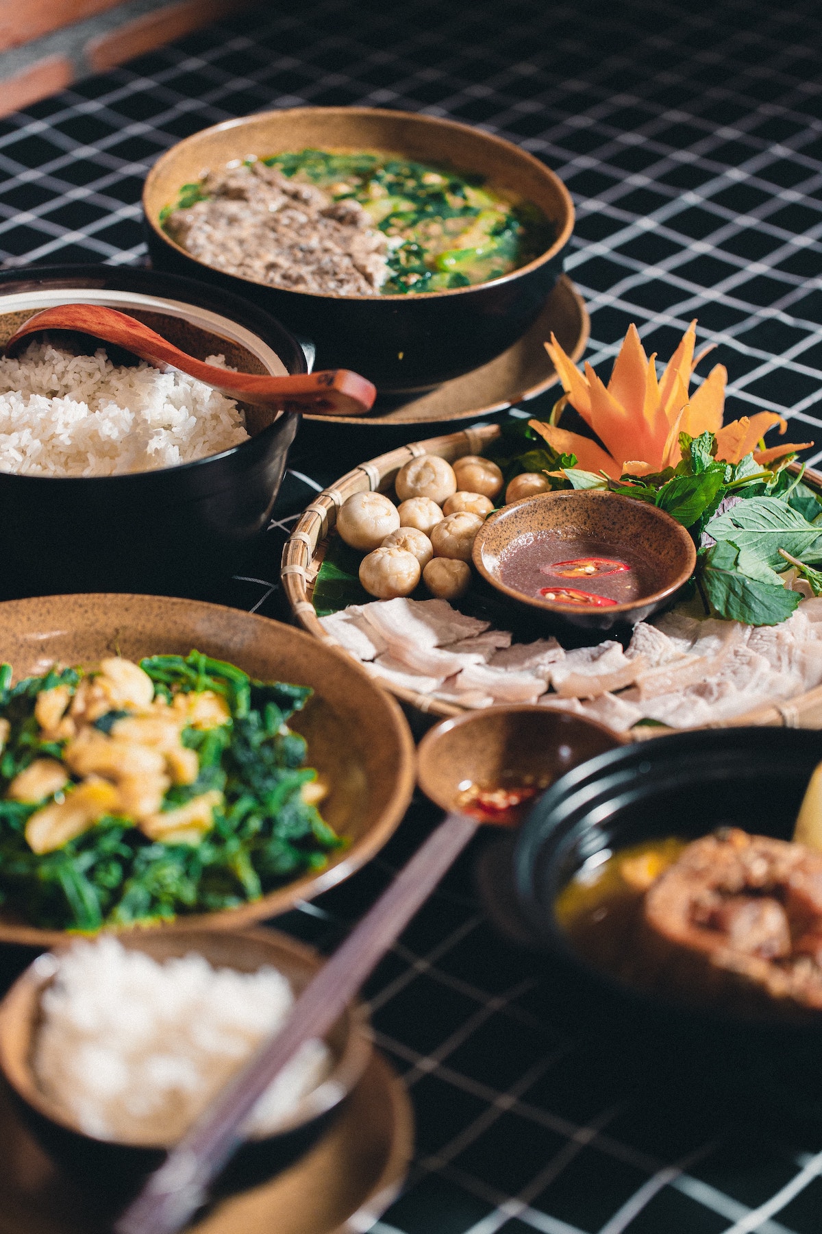 Several plates of Vietnamese food on a black surface