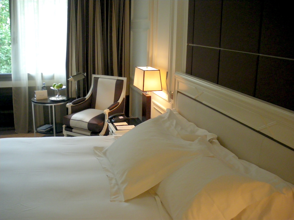 Hotel guest room with white double bed in the foreground.