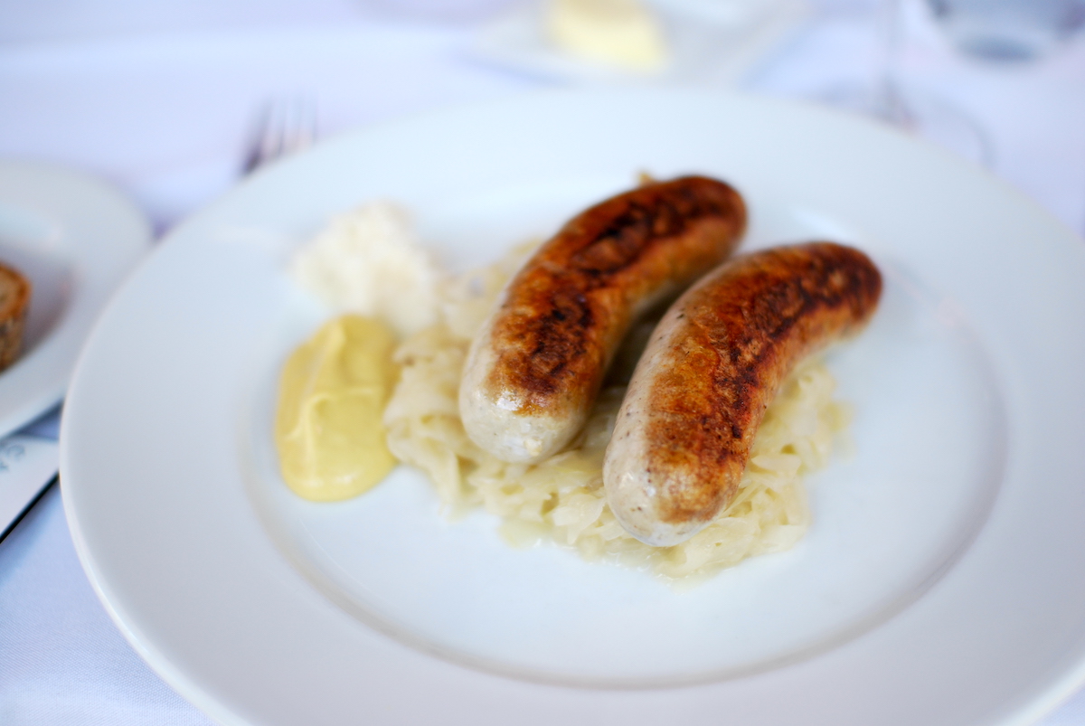 Two small bratwurst served over a bed of sauerkraut