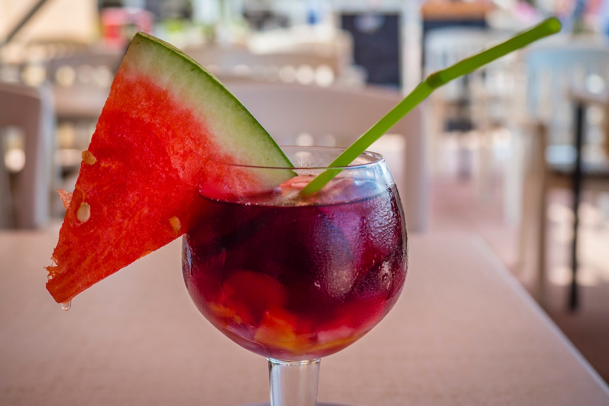 Glass of sangria garnished with a triangular slice of watermelon