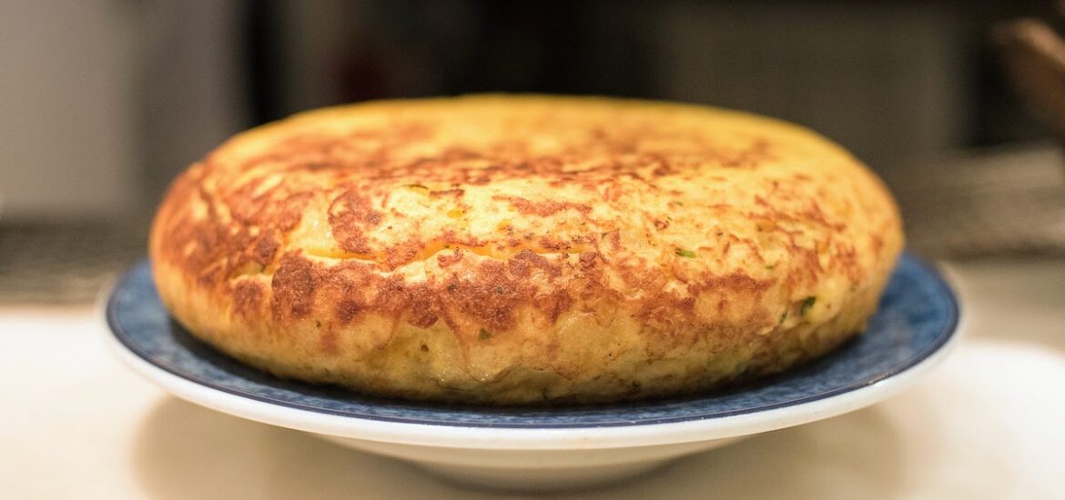 A whole Spanish omelet on a blue and white plate.