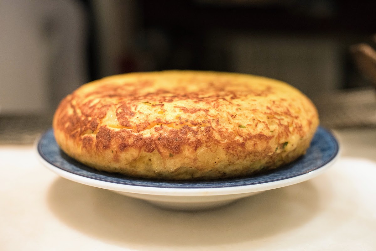 A whole Spanish omelet on a blue and white plate.