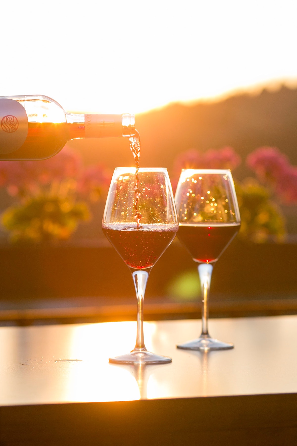 Two glasses of red wine being poured at sunset