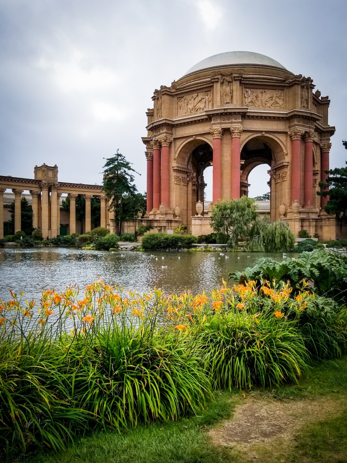 Shot of the domed rotunda of the Palace of Fine Arts in San Francisco, with a pond and lots of beautiful foliage on the banks 