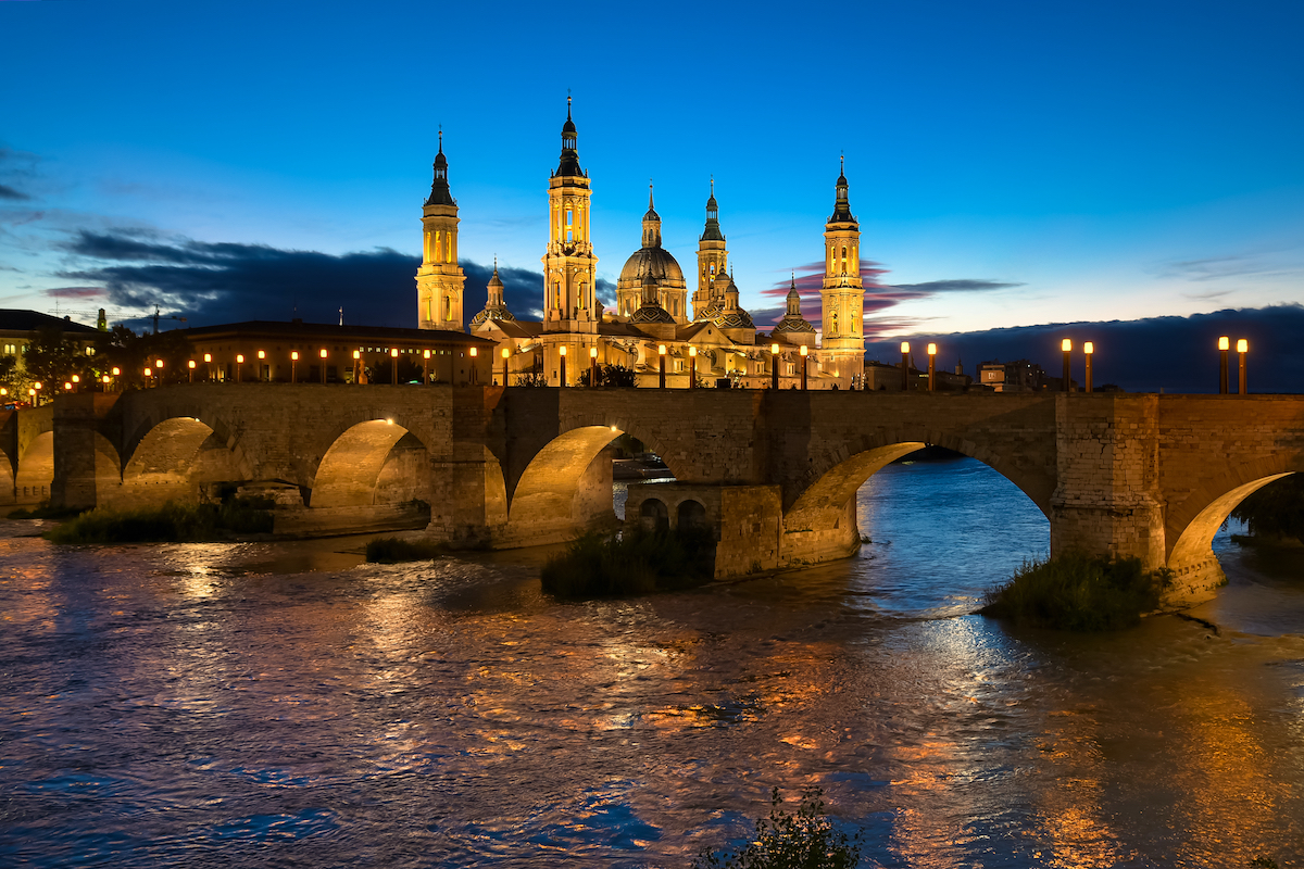 Evening view of large cathedral and stone arched bridge.