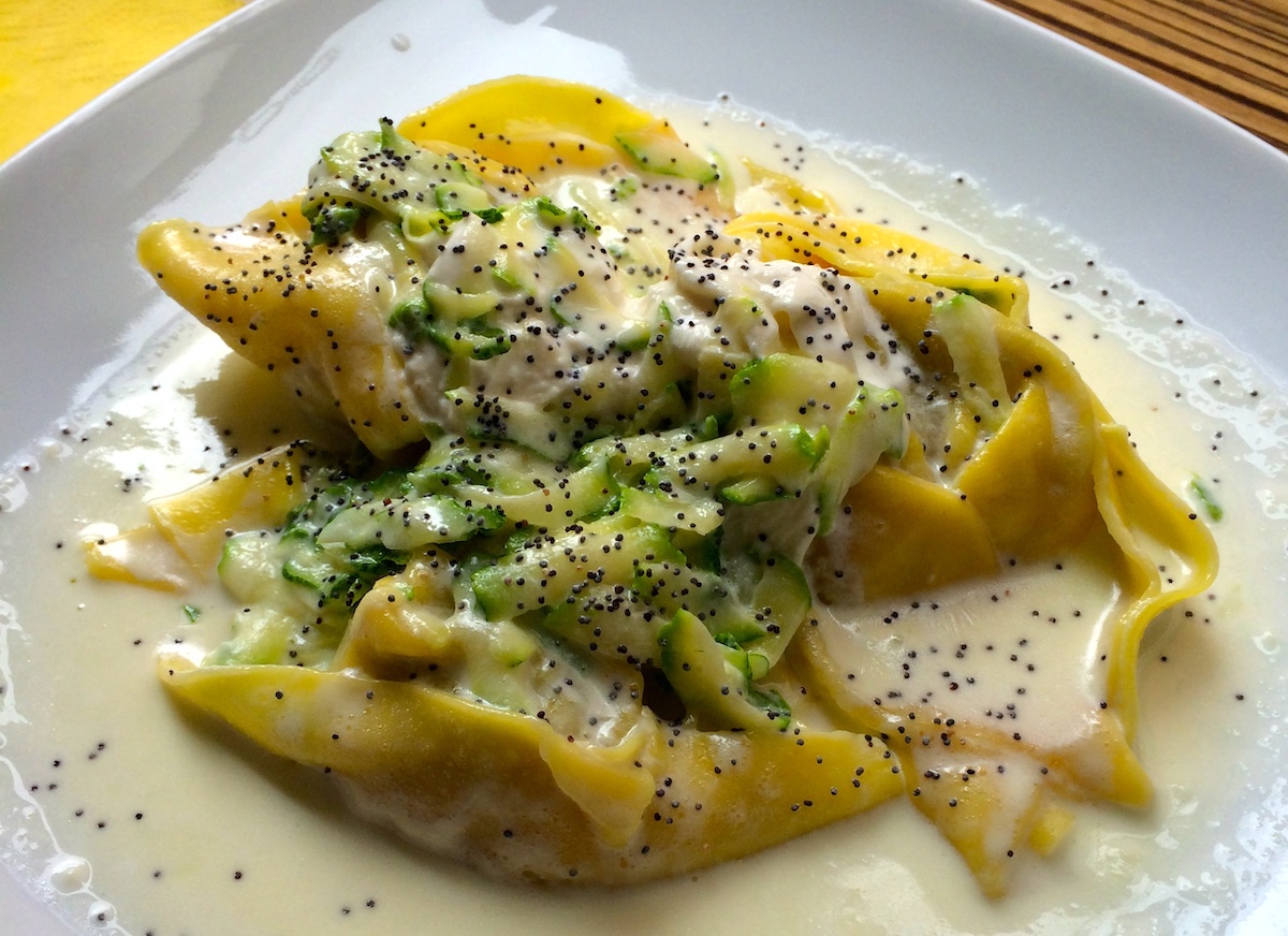 Large pasta noodles in a light cream sauce with green vegetables and poppyseeds